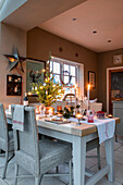 Lit candle on dining table with wicker chairs in Cheshire home UK