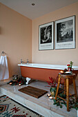 Braune freistehende Badewanne mit Schwarz-Weiß-Drucken und Weihnachtsdekoration in einem Haus in Berkshire, England