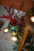 Red berries and lit tealights with wooden stool in Berkshire home UK