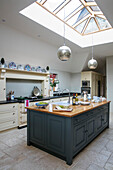 Silver pendant light above teal workbench with skylight in Dorset farmhouse kitchen UK