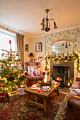 Lichtergirlande auf Kamin im Wohnzimmer mit Holztisch und Baum in georgianischem Landhaus Liverpool UK