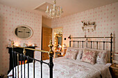 Black metal framed bed with lit fairylights and oval mirror in Georgian cottage Liverpool UK