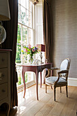 Cut flowers on desk at window with chair in detached Sussex country house UK