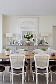 White painted chairs at wooden dining table in detached Sussex country house UK