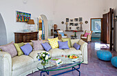 Fliederfarbene Kissen auf geschwungenem Sofa mit gläsernem Couchtisch im Wohnzimmer einer italienischen Villa an der Amalfiküste
