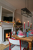 Beleuchtete Kerzen auf einem hölzernen Esstisch zu Weihnachten in einer Wohnung in Hove, East Sussex, Großbritannien