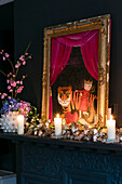 Vergoldetes gerahmtes Kunstwerk und brennende Kerzen auf dem Kaminsims in der Wohnung in Hove, East Sussex, Vereinigtes Königreich