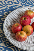 Rosy apples on fruit bowl with blue patterned fabric in Victorian terrace house South London UK
