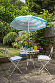 Striped parasol over garden furniture on terrace in Victorian townhouse garden South London UK