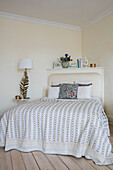 White bed cover with gilt lamp in corner of room in West Sussex townhouse UK