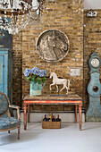 Reiterrelief an einer Backsteinmauer mit alterndem Tisch und Uhr in einem umgebauten Schulhaus im Süden Londons (UK)