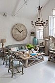 Large wooden clock face with low table and sofa in whitewashed South London schoolhouse conversion UK