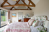 Schlafzimmer mit hoher Balkendecke und eigenem Bad in einer umgebauten Scheune in Gloucestershire UK