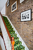 Gerahmte Drucke über schwarzem und grünem geometrischem Teppichboden im Treppenhaus eines viktorianischen Londoner Stadthauses UK
