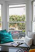 Türkisfarbene Kissen auf der Fensterbank mit Blick auf den Hinterhof in einem Haus in London, UK
