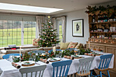 Blauer und weißer Esstisch mit Weihnachtsbaum in einem Haus aus den 1930er Jahren im Stil des Arts and Crafts in West Sussex, Großbritannien