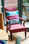 'Home wasn't built in a day' cushion on pink armchair in Arts and Crafts home Sevenoaks Kent UK