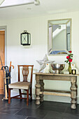 Chair and table with mirror and umbrella stand in entrance hallway of Somerset farmhouse UK