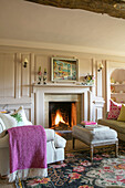 PInk blanket on armchair at lit fireside in Somerset home UK