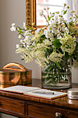 Weiße Blumen und Adressbuch auf hölzernem Tisch im Hausflur in Hampshire, England
