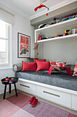Rote Kissen und Spielzeug mit grauem Tagesbett in einem Haus im Norden Londons UK