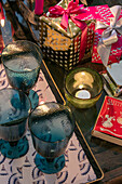 Blaue Gläser und Teelicht mit eingepackten Weihnachtsgeschenken in einem Haus in East Dulwich, London UK
