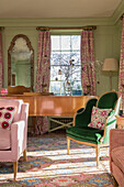 Music room with pink floral curtains and green velvet armchair in Georgian home Hertfordshire England UK
