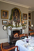 Gilt framed artworks and ivy surround fireplace in Georgian dining room Hertfordshire England UK
