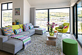 Light grey sofa in living room with view of coastal hillside Cornwall UK
