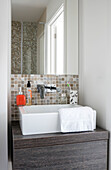 Beige mosaic tiling below mirrored cabinet with washbasin in newbuild Cornwall UK