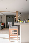 Light grey stools at breakfast bar with fruit in open plan kitchen of Hampshire home UK