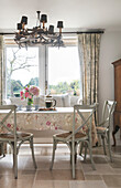 Painted chairs at table with floral cloth in Oxfordshire home UK