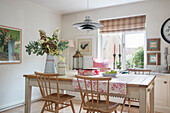 Wooden chairs at table with pendant light and cut flowers in Kent home UK