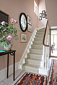 Peony on console in hallway with circular mirror over stairs London home UK