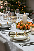 Weihnachtsgebäck und brennende Kerzen mit duftenden Orangen auf einem Esstisch in einem Haus in Hampshire, Großbritannien