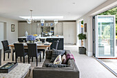 Open plan kitchen living room with open doors to garden in Sussex home UK