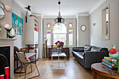 Schwarzes Ledersofa und Regal im Wohnzimmer einer Londoner Terrasse UK