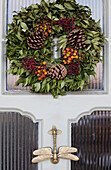 Tannenzapfen und Beeren im Weihnachtskranz an der Haustür mit Libellenklopfer Norwich UK
