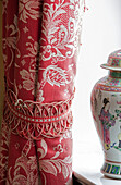 Red floral curtains with tieback and Chinese urn in Sussex home