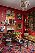 Sammlung von Kunstwerken und beleuchtetes Feuer mit Tulpen im Wohnzimmer in Sussex