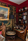 Wooden bookcase and lamp with gilt framed artwork and tapestry in Sussex home