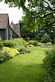 Summer borders and lawn path in grounds of 1900s former coach house West Sussex England UK