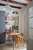Small table and stools with grey cupboard and shelves in Issigeac kitchen Perigord France