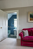 PInk sofa at bathroom doorway in Hampshire home England UK