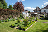 Flowerbeds and paths with lawn in garden of of Grade II listed semi-detached country house Hertfordshire UK