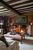 Framed oil painting above lit fire with ottoman in Kent farmhouse UK