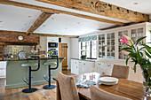 Light green barstools with wooden table in open plan timber framed Kent farmhouse kitchen UK