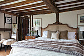 Wicker headboard and fur throw with chair in timber framed Kent farmhouse UK