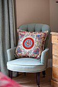 Handmade cushion on light green chair in corner of North London bedroom UK