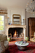 Italian chandelier with gilt mirror above open fire with Chinese drums in French chateau Lot et Garonne